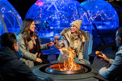 A group sitting around a fire by the igloos