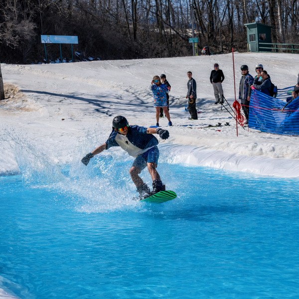 Snowboarder sliding across the pond skim