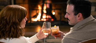 A couple enjoying cocktails by the lobby fireplace