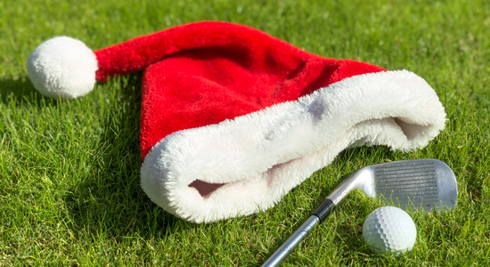 Santa's hat, golf club and golf ball laying in the grass