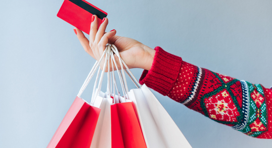 Woman's hand in festive sweater with holiday gift bags