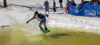 Snowboarder sliding across the pond skim