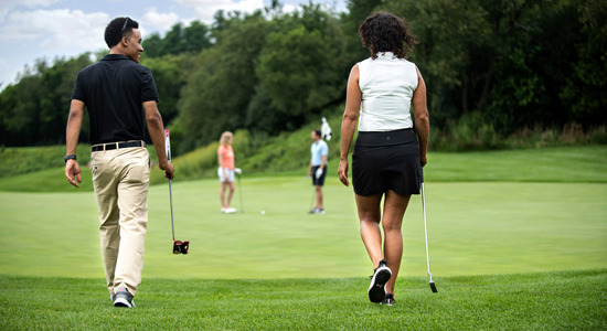 Man and woman walking with golf clubs on course