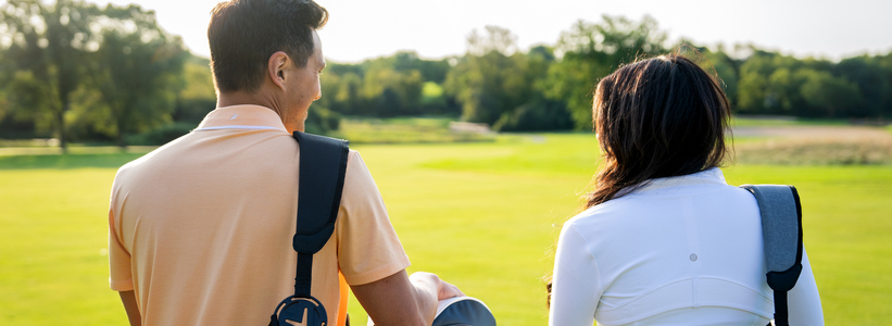 Couple walking on the golf course with their golf bags